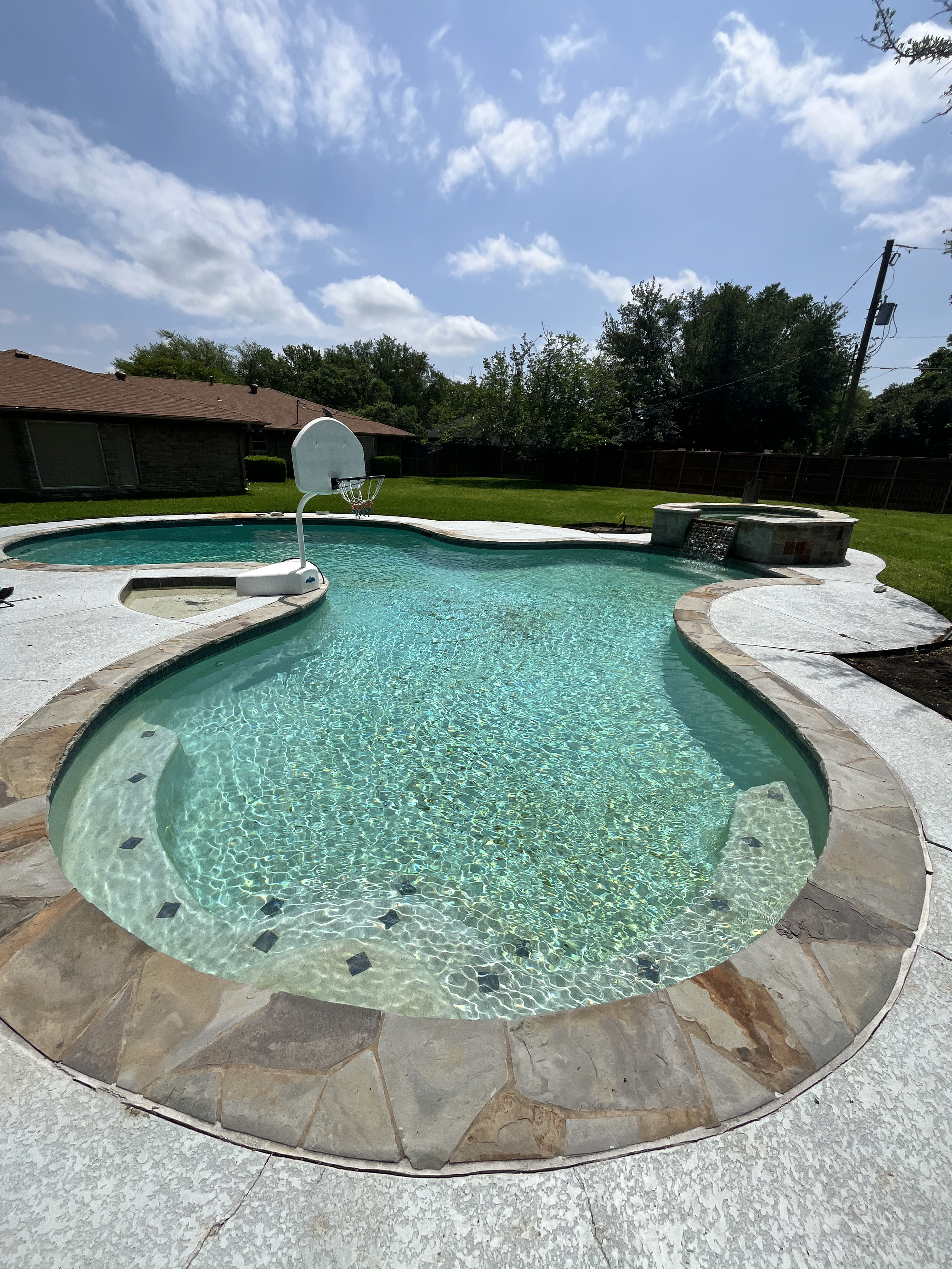 Clean freeform pool and raised spa in Las Colinas TX serviced with weekly pool and spa cleaning near Lake Carolyn