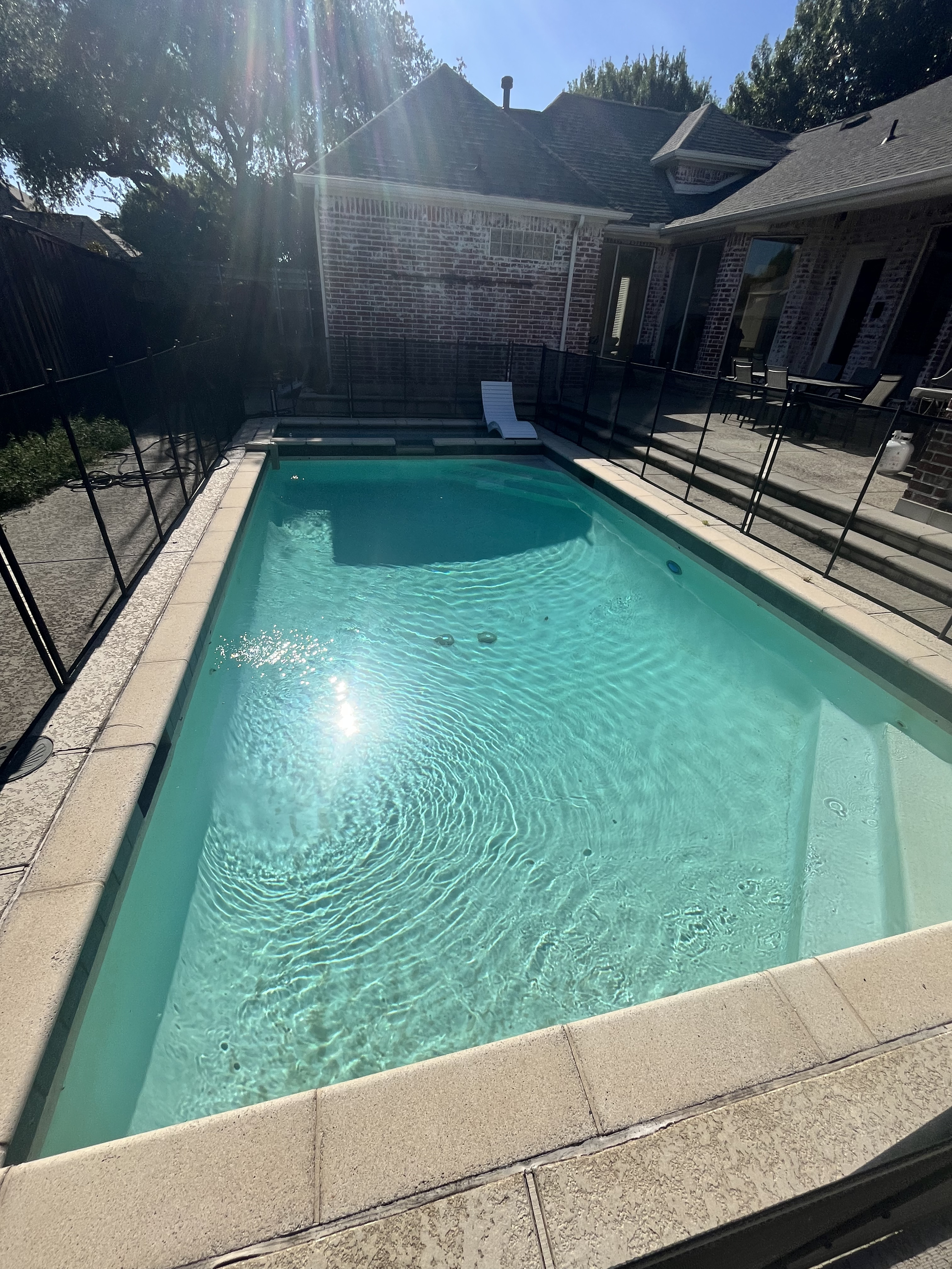 Sparkling clean rectangular backyard pool in Coppell TX after weekly pool maintenance, brushing, and sanitizer balancing